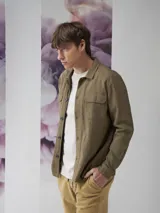 Camisa color verde militar de manga larga con cuello clásico, cierre frontal con botones y dos bolsillos de parche en el pecho.