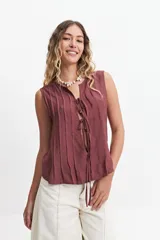 Blusa sin mangas color beige con lazo frontal y textura liviana.