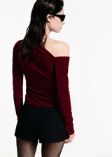 Top de terciopelo rojo con un solo hombro, manga larga y frunces laterales.