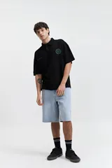 Polo negra de corte oversize con logo estampado en el pecho.