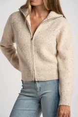 Cardigan de punto color beige melange con textura tweed, cuello alto y cierre frontal metálico. Corte ajustado al cuerpo y manga larga.