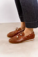 Náuticos color beige con diseño calado geométrico, cordones decorativos y suela marrón.