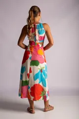 Vestido largo con estampado de flores en tonos naranja, rojo, verde y celeste. Tiene escote halter, espalda descubierta y aberturas en la cintura.