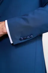 Traje de vestir azul con solapa de satén, compuesto por saco con cierre de un botón, pantalón de corte entallado y moño de satén azul.