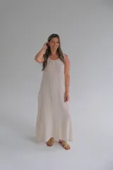 Vestido largo color beige de lino italiano sin mangas, con escote redondo y detalle trenzado que resalta su caída suave. Cuenta con bolsillos en los costados.