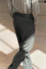 Pantalón de tiro medio color verde oscuro, confeccionado en hilatura con viscosa. Cintura con trabillas, bolsillos delanteros, pierna ancha y cierre frontal con cremallera, botón y gancho metálico.