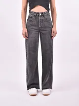 Jean de mujer color rojo, tiro alto, corte recto y largo. Presenta roturas en la zona de los muslos y ruedo deshilachado.