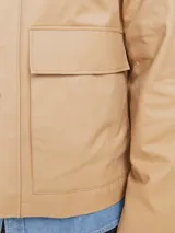 Campera color beige estilo workwear con cuello de pana marrón, cierre frontal con botones a presión, mangas largas y bolsillos frontales con solapa.