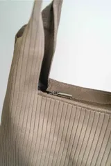 Bolso negro tipo tote bag con textura acanalada y asas de hombro.