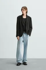 Blazer azul marino de corte recto, confeccionada en tejido con viscosa. Tiene cuello con solapas de muesca, manga larga con puño abotonado, bolsillo de vivo en el pecho y bolsillos de parche en la cadera. El bajo tiene aberturas en la espalda y el cierre es con botonadura frontal.