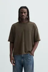 Camiseta marrón de corte holgado, cuello redondo y manga corta. Tiene un efecto lavado y terminaciones irregulares.