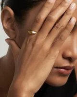 Anillo dorado con superficie plana en forma de pera.