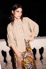 Camisa beige de algodón con mangas murciélago y botones rayados.