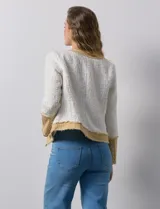 Chaqueta Nanette en tejido tweed color crudo con detalles en denim azul. Tiene cuello a la base, abertura central, bolsillos delanteros, puños con aplique de botones perlados, terminación desflecada y forro interno.