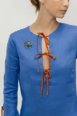 Vestido corto azul con escote en V y lazos marrones en mangas y escote.