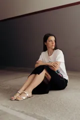 Sandalias negras de cuero con tira ancha sobre el empeine y tira entre los dedos, ambas adornadas con apliques metálicos plateados.