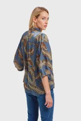 Camisa celeste con estampado de hojas marrones, de mangas 3/4 abullonadas y cuello clásico.