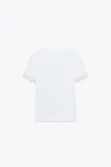 Camiseta blanca de algodón con cuello redondo y mangas cortas con detalle de encaje negro.