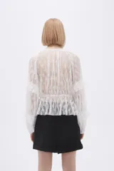 Blusa blanca traslúcida de encaje con mangas largas abullonadas y volados.