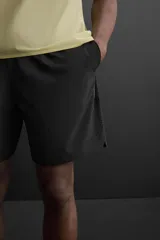 Shorts de entrenamiento negros confeccionados en tejido técnico ligero y elástico, con cintura elástica ajustable con cordón interior, bolsillos frontales y bolsillo trasero con cierre de cremallera. Bajo con acabado termofijado y aberturas laterales.