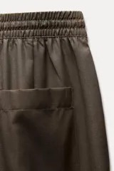 Pantalón de tiro medio color marrón, con cintura elástica ajustable con cordones, bolsillos delanteros y traseros, raya planchada y pierna recta.
