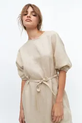 Vestido midi color coral confeccionado en lino. Tiene corte recto, mangas abullonadas con detalle de tablas en el puño, tajos laterales y lazo en la cintura.