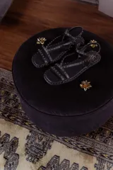 Sandalias chatitas negras de cuero con múltiples tiras finas y tachas doradas.