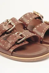 Sandalias marrones de cuero vacuno con doble tira y hebillas metálicas ajustables.