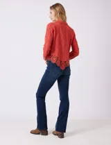 Camisa de algodón color naranja, con bordado suizo y encaje calado. Tiene cuello con solapa, botones frontales, mangas largas con terminación de encaje y ruedo asimétrico con galón de encaje.