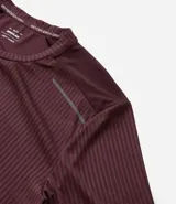 Remera deportiva de manga corta y cuello redondo, color beige claro, con textura acanalada vertical. Presenta detalles reflectantes en los hombros.