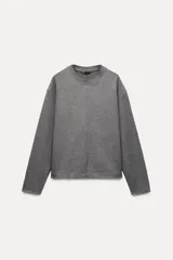 Sweater gris de cuello redondo y manga larga.