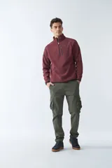 Buzo polar de algodón color bordó, con cuello elevado, medio cierre frontal, bolsillo con cierre en el pecho y logo estampado.