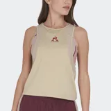Musculosa deportiva Le Coq Sportif color beige melange, con paneles laterales en tono rosado claro y logo del gallo en color bordó.