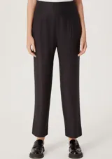 Pantalón negro de corte carrot con cintura alta y pinzas frontales.