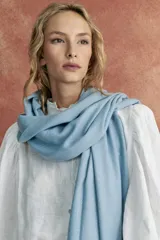 Bufanda celeste con pequeños puntos brillantes y flecos en los extremos.