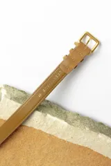 Cinturón marrón de gamuza con hebilla dorada.