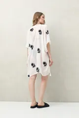 Poncho de gasa liviana color blanco, con bordados florales negros y detalles de borlas en el borde.