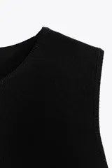 Top negro de punto con cuello redondo y sisa. El bajo es abullonado con elástico interior.