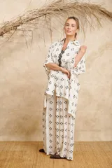 Camisa amplia de lino color blanco con bordado de flores negras, corte irregular con espalda más larga.