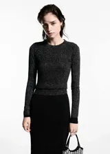 Jersey de punto fino negro con lúrex plateado, cuello redondo y manga larga.