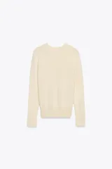 Sweater negro de punto liso con cuello redondo y mangas largas con botones dorados en los puños.