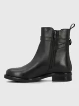 Bota corta de cuero negro con caña media, detalle de tira con hebilla metálica en el tobillo y elástico lateral. Cuenta con suela plana y taco bajo cuadrado.