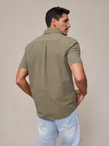 Camisa de algodón blanca de manga corta, con cuello abotonado y botones frontales.