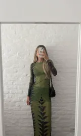 Vestido midi ajustado de microtul verde con estampado abstracto en tonos oscuros. De mangas largas y cuello redondo, es una prenda transparente y elástica.