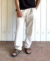 Pantalón de lino beige y crudo a rayas, de corte ancho y relajado.