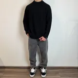 Sweater negro de tejido de punto grueso, con cuello alto y mangas raglán. Corte holgado.