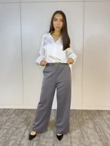 Pantalón de vestir gris con corte palazzo, cintura alta con elástico y cinturón con hebilla dorada.