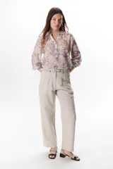 Pantalón de lino color blanco, tiro alto, corte recto y holgado, con pinzas delanteras y pespuntes a contratono.