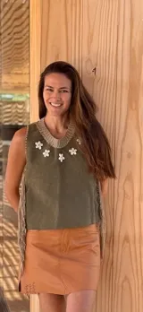 Top color beige de cuero con flecos en los laterales y caracoles buzios en el frente. Espalda tejida.