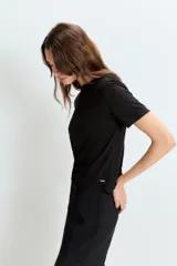 Remera negra con espalda descubierta y tiras doradas de corpiño a la vista.